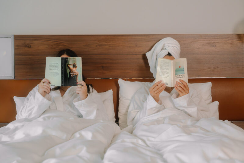 Two guests reading a book in bed