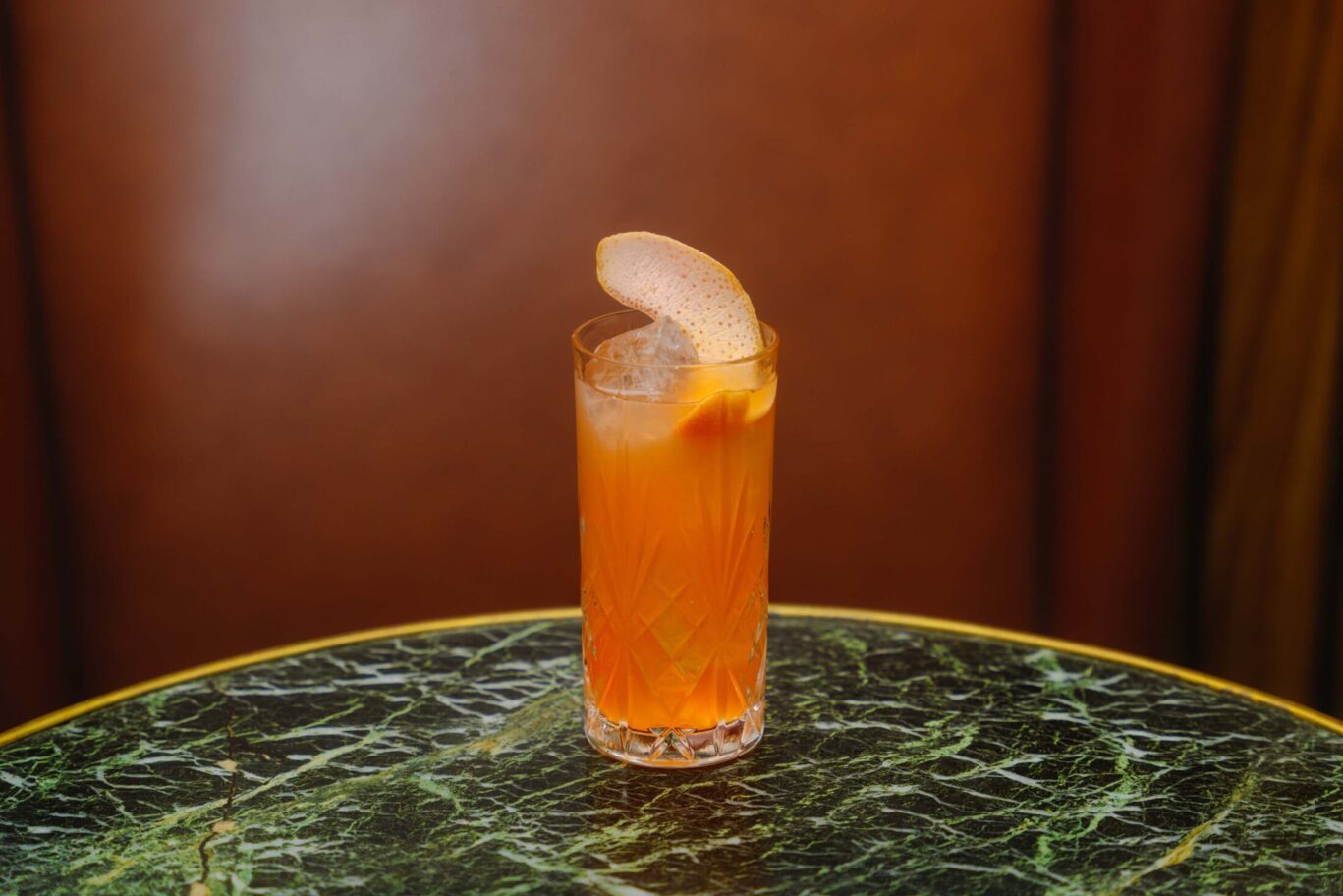 Orange cocktail on green marble table of Bar 1910