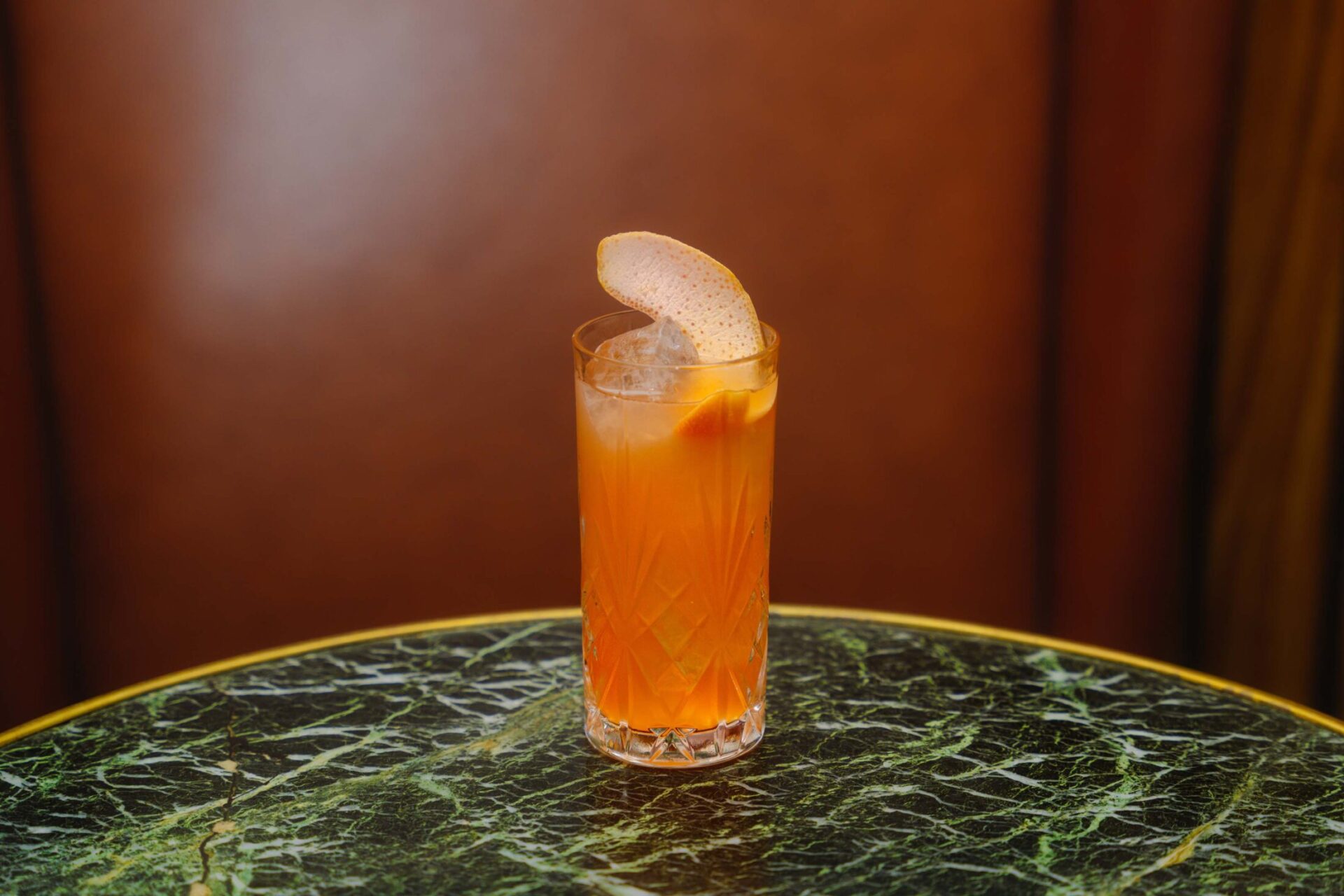 Orange cocktail on green marble table of Bar 1910